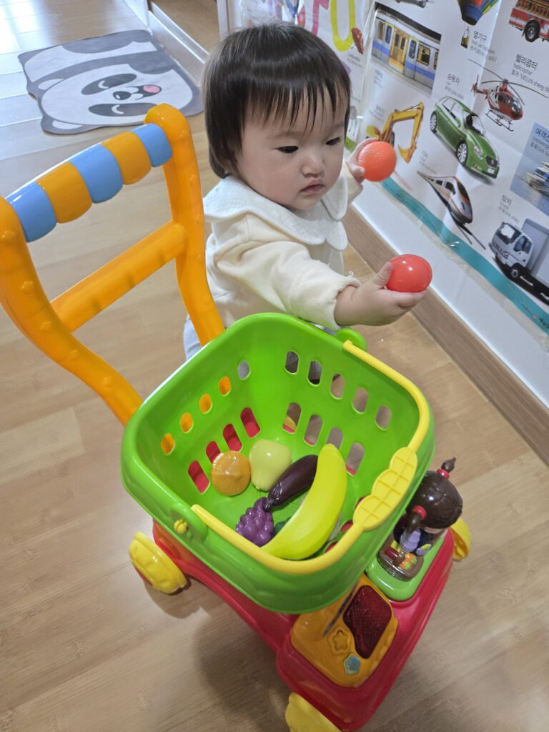아이가 콩순이 쇼핑카트로 마트놀이 하는 장면